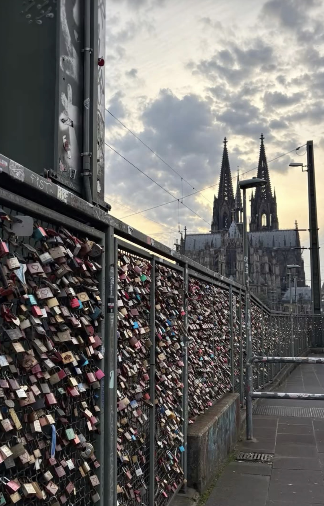 Love locks on a bridge railing with Cologne Cathedral behind
