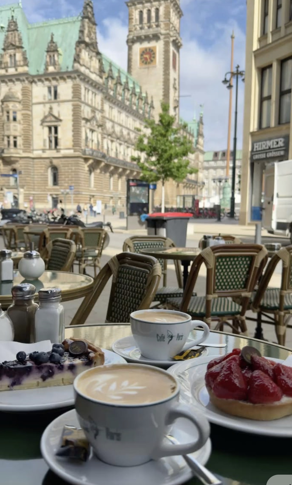 Coffee and cake at an outdoor table with Hamburg City Hall behind