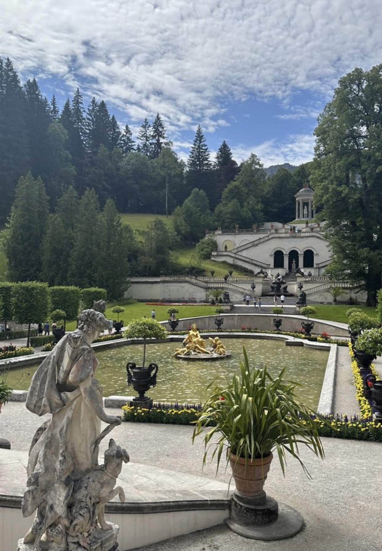 A palace garden with stone statues and a golden fountain